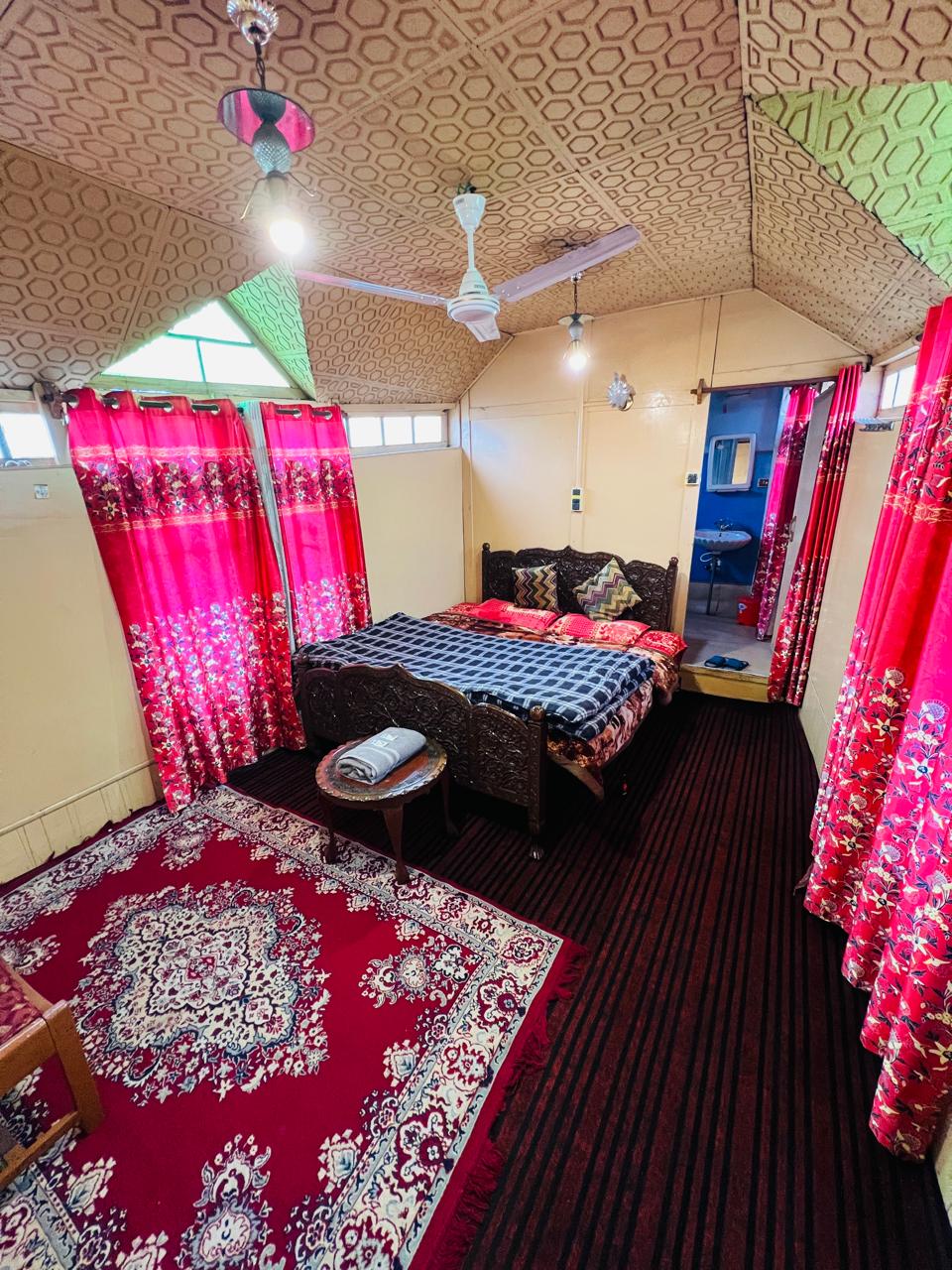 Deluxe bedroom with carved wooden bed frame and Kashmiri carpet