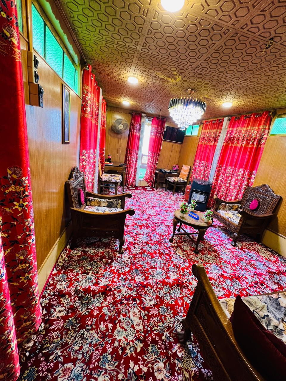 Heritage drawing room with chandelier, carved wooden chairs and red floral carpet